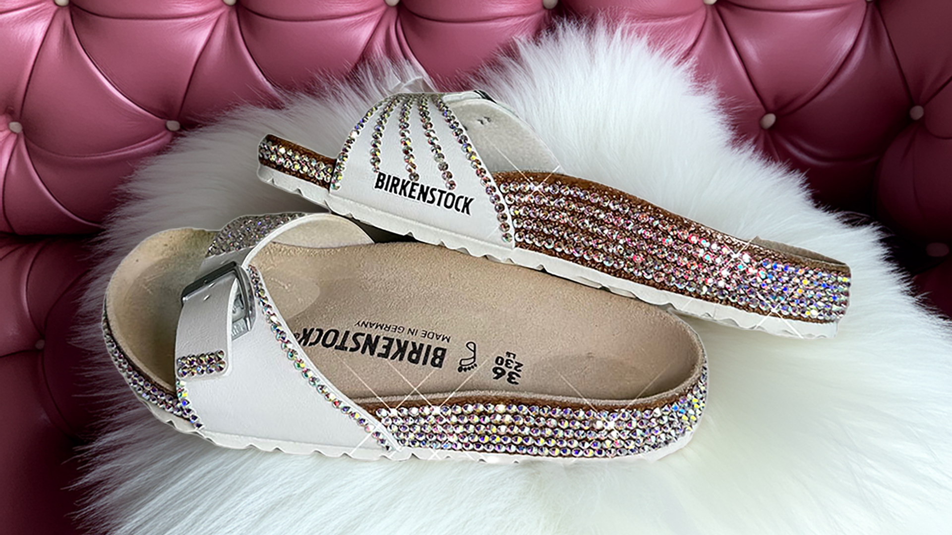 Pair of Birkenstock sandals with rhinestone embellishments on a fluffy white rug.
