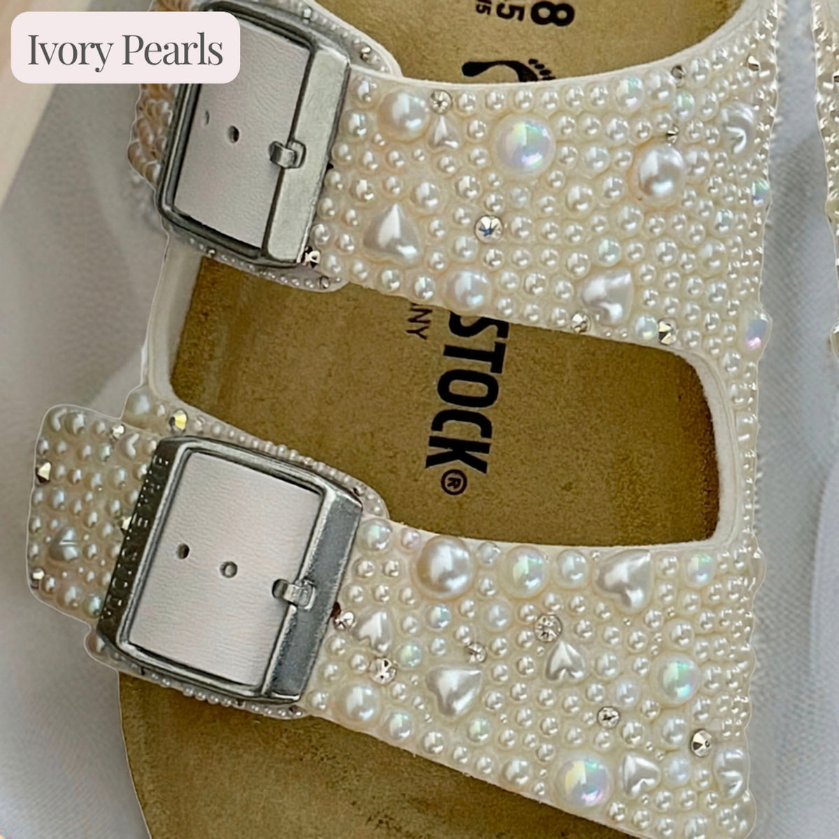 Close-up of white Birkenstock Arizona sandal straps with ivory pearls, delicate pearl hearts and crystal accents.
