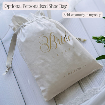 White drawstring shoe bag personalised with “Bride”, plus an example name and wedding date in gold lettering. Sold separately.
